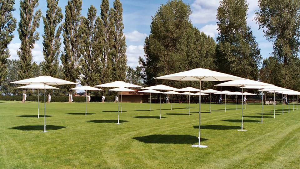 dozens of p2 single pole umbrellas setup and staged in a grass field