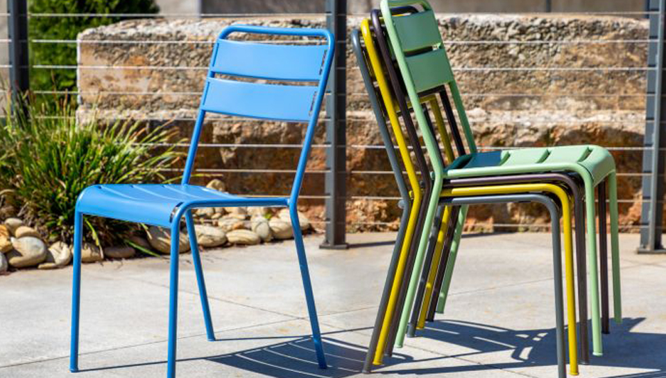 a single outdoor stacking chair next to a stack out outdoor stacking chairs